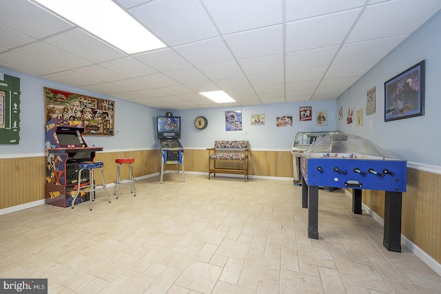 playroom with a drop ceiling and wooden walls