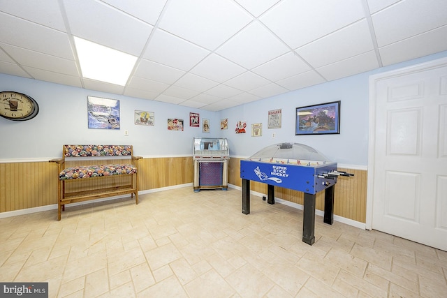 playroom with a drop ceiling and wood walls