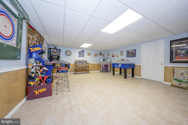 game room featuring a drop ceiling and wood walls