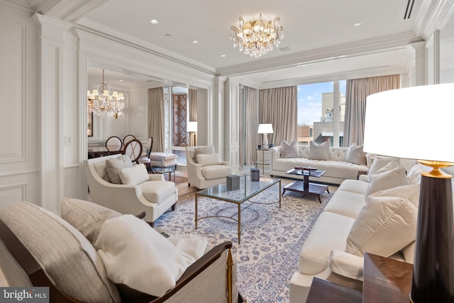 living room featuring hardwood / wood-style floors, decorative columns, an inviting chandelier, and crown molding