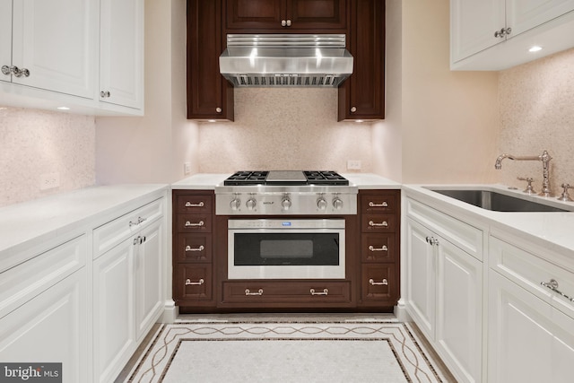 kitchen with white cabinetry, wall chimney range hood, sink, and appliances with stainless steel finishes