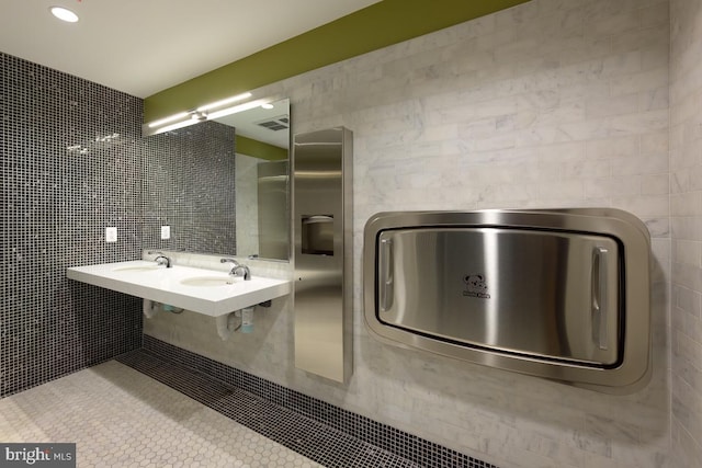 bathroom with tile patterned floors, tile walls, and dual sinks