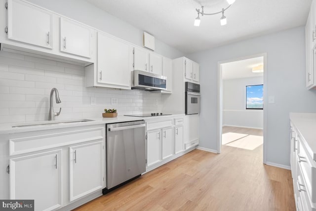 kitchen with light hardwood / wood-style floors, white cabinetry, sink, and appliances with stainless steel finishes