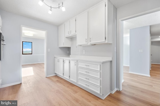 kitchen featuring white cabinetry, a textured ceiling, and light wood-type flooring