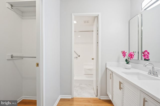 bathroom with hardwood / wood-style floors, vanity, and walk in shower