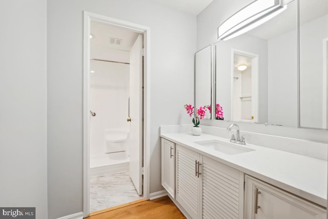 bathroom with hardwood / wood-style flooring, vanity, and a shower