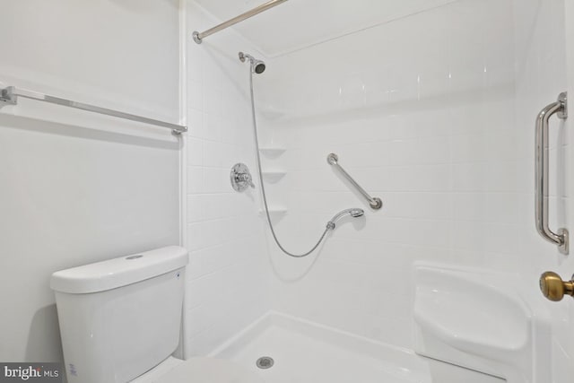 bathroom with a tile shower and toilet