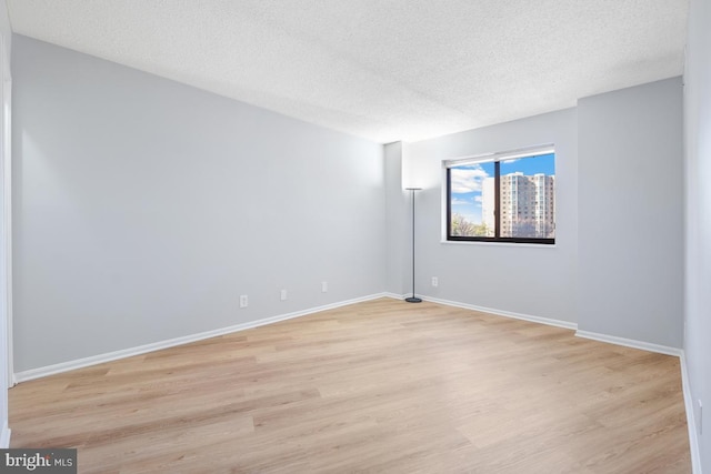 empty room with a textured ceiling and light hardwood / wood-style floors