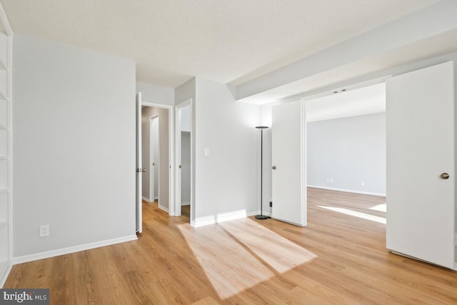 spare room with a textured ceiling and light hardwood / wood-style flooring