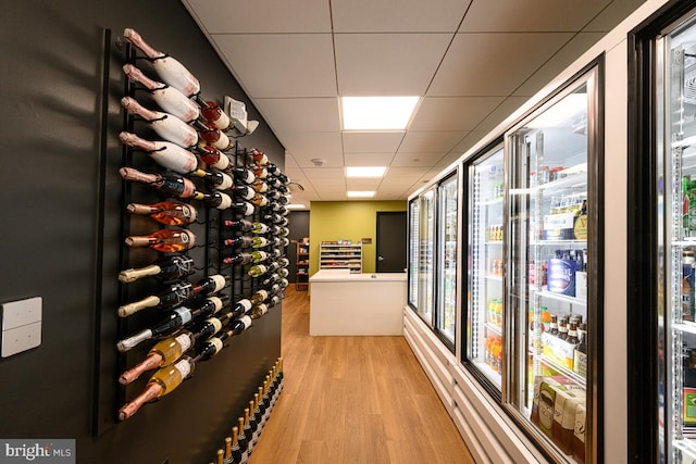 wine area with a paneled ceiling, plenty of natural light, and light hardwood / wood-style floors