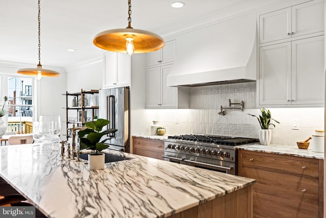 kitchen featuring decorative light fixtures, premium range hood, white cabinetry, and high quality appliances