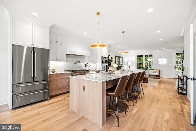 kitchen featuring light hardwood / wood-style flooring, appliances with stainless steel finishes, a kitchen island with sink, white cabinetry, and light stone counters