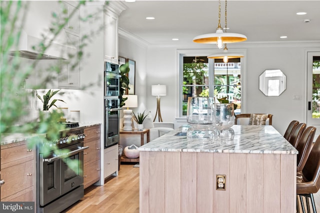 kitchen with light wood-type flooring, light stone counters, and decorative light fixtures