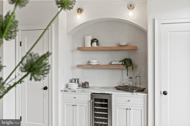 bar featuring light stone counters, white cabinetry, and wine cooler