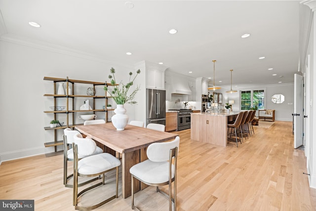 dining area featuring crown molding and light hardwood / wood-style flooring