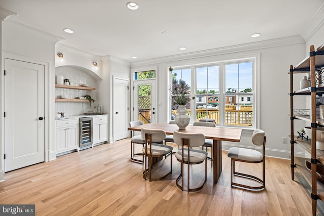 dining space with light wood-type flooring, crown molding, and wine cooler