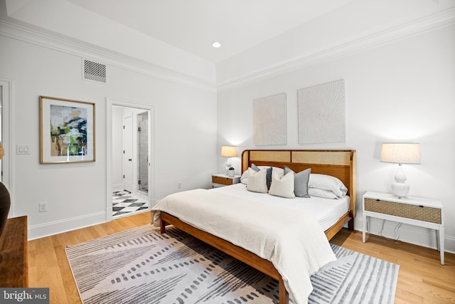 bedroom with ornamental molding, light hardwood / wood-style floors, and ensuite bathroom