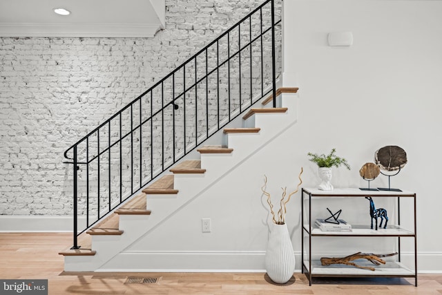 stairs featuring hardwood / wood-style floors and ornamental molding