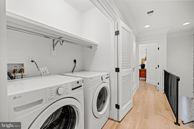 clothes washing area featuring ornamental molding, light hardwood / wood-style flooring, and washing machine and dryer