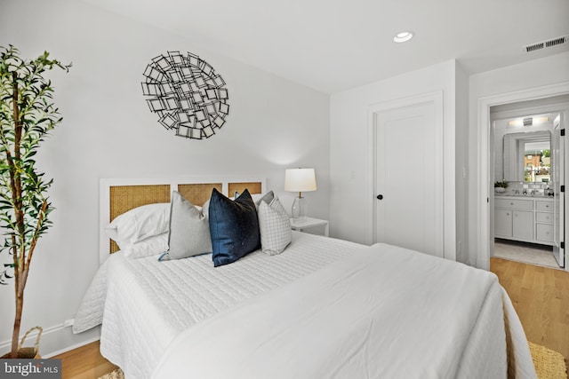 bedroom featuring light wood-type flooring and ensuite bathroom