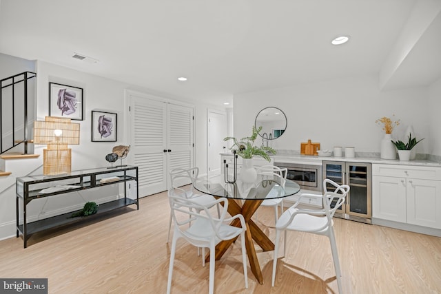 dining space featuring light hardwood / wood-style flooring and beverage cooler