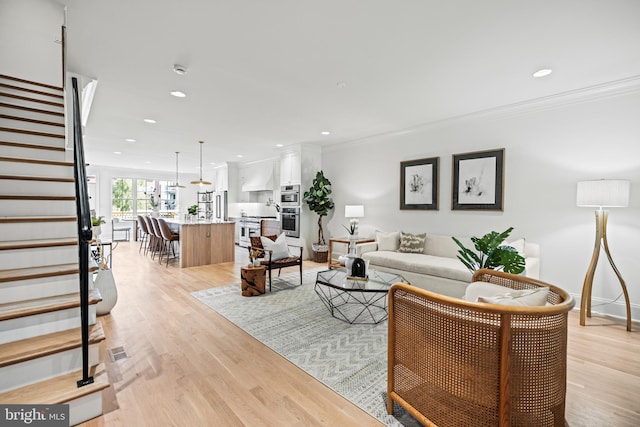 living room with crown molding and light wood-type flooring