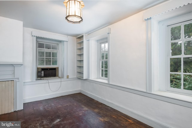 unfurnished dining area with a healthy amount of sunlight, cooling unit, and dark hardwood / wood-style floors