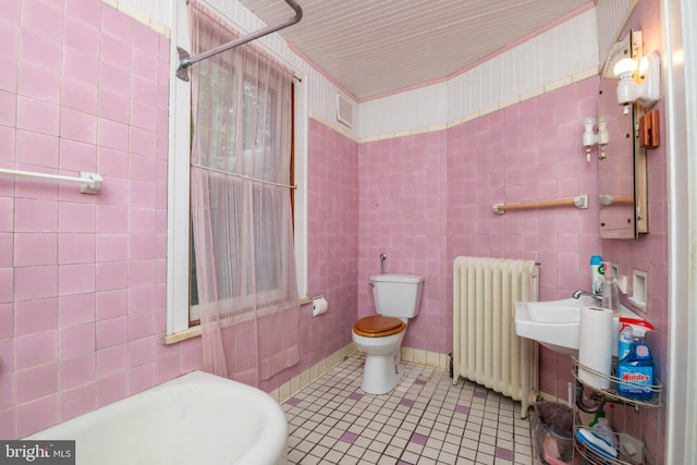 bathroom featuring toilet, radiator, tile walls, and tile patterned flooring