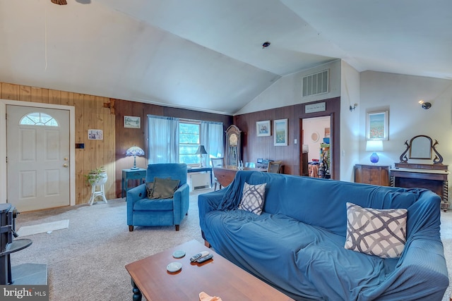 carpeted living room with high vaulted ceiling and wooden walls