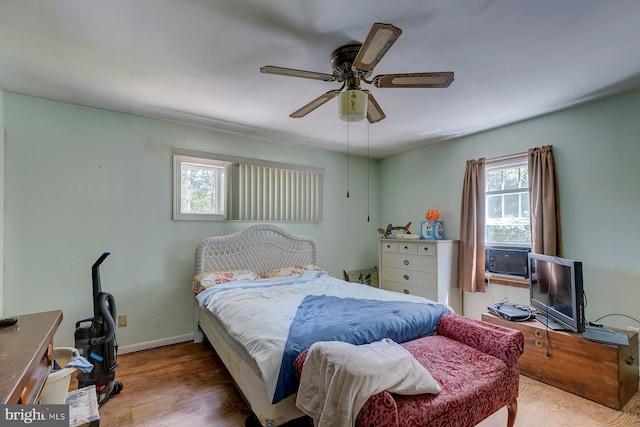 bedroom with multiple windows, hardwood / wood-style flooring, cooling unit, and ceiling fan