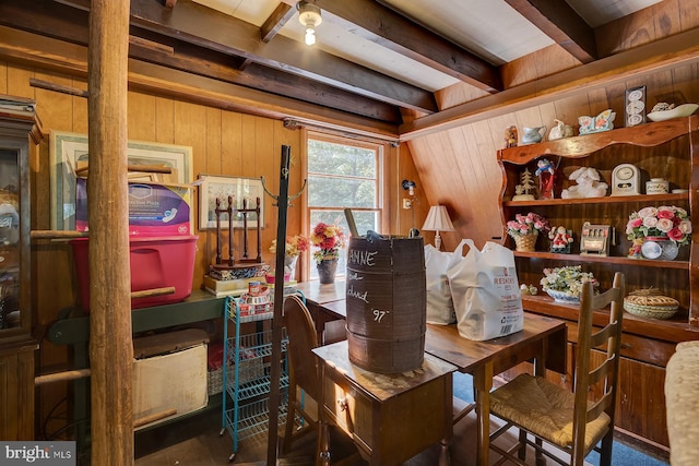 dining room featuring wooden walls and beamed ceiling