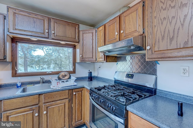 kitchen with gas stove, a sink, decorative backsplash, under cabinet range hood, and brown cabinets