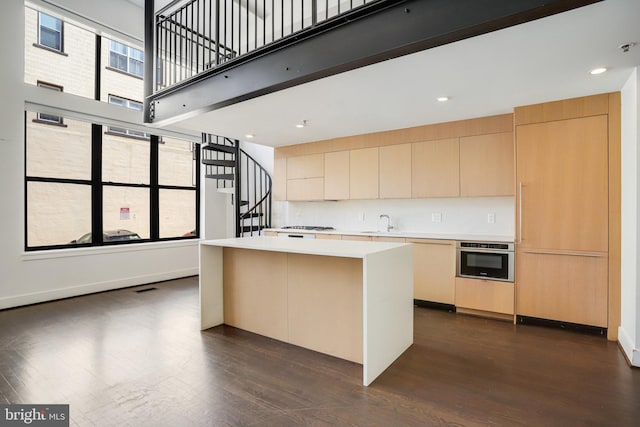 kitchen with oven, a center island, dark wood-type flooring, sink, and decorative backsplash