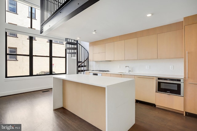 kitchen with dark hardwood / wood-style floors, backsplash, a center island, stainless steel appliances, and sink