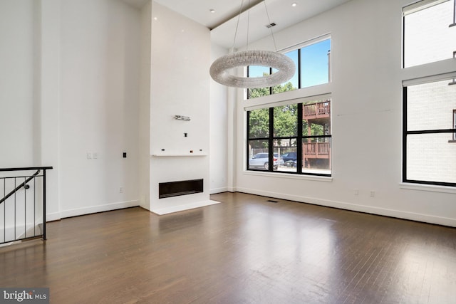 unfurnished living room with dark wood-type flooring and a high ceiling