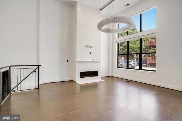 unfurnished living room featuring dark hardwood / wood-style floors and a towering ceiling