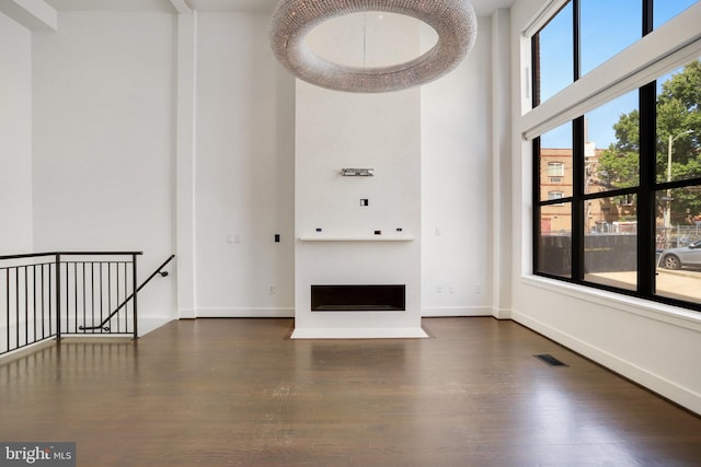 unfurnished living room featuring a high ceiling and dark hardwood / wood-style floors