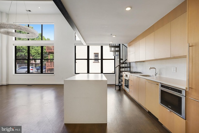 kitchen featuring backsplash, a center island, appliances with stainless steel finishes, sink, and dark hardwood / wood-style floors