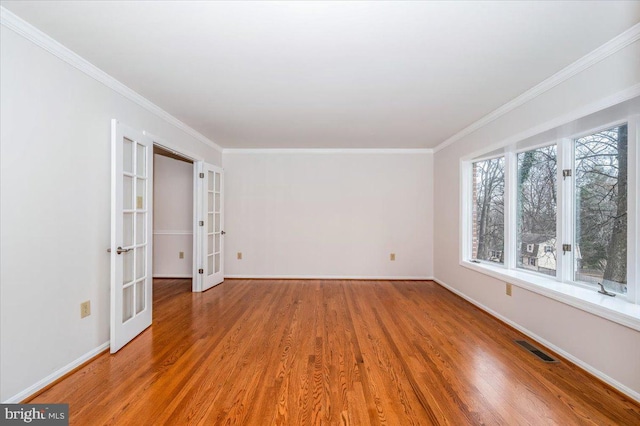 empty room with hardwood / wood-style flooring, ornamental molding, and french doors