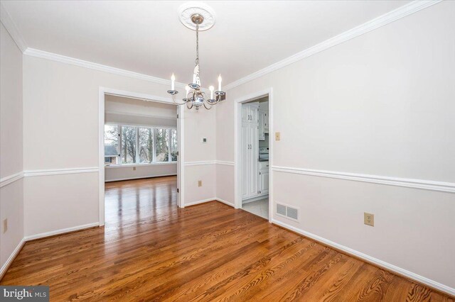 unfurnished dining area featuring crown molding, a chandelier, and hardwood / wood-style flooring