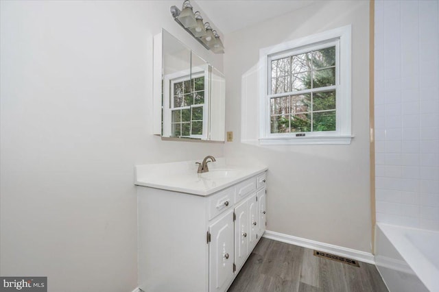 bathroom with a bath, vanity, and wood-type flooring