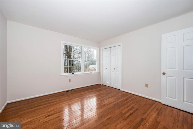 unfurnished bedroom with dark hardwood / wood-style floors and a closet