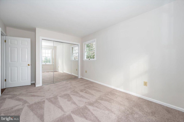 unfurnished bedroom featuring light carpet and a closet