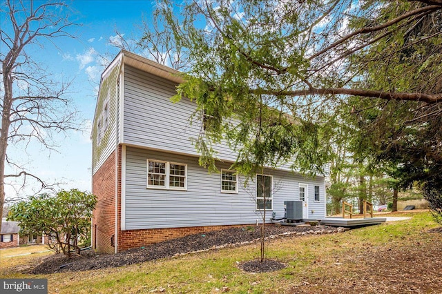 rear view of property featuring a lawn and cooling unit