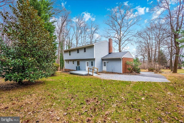 rear view of property featuring a lawn and a deck