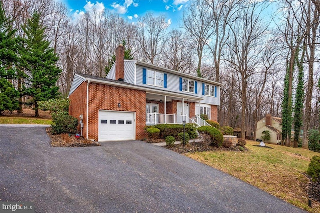 view of front property with covered porch, a garage, and a front lawn