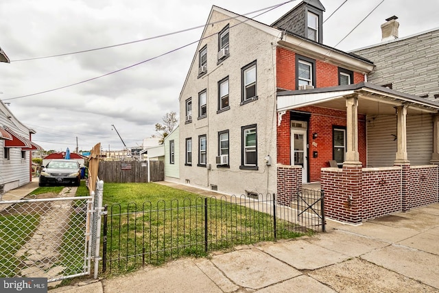 view of home's exterior with a fenced front yard, a yard, a porch, and brick siding