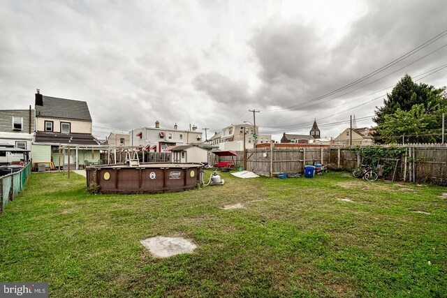 view of yard with a fenced in pool, a storage unit, a residential view, a fenced backyard, and an outdoor structure