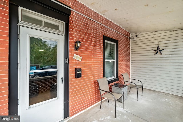 property entrance featuring covered porch and brick siding