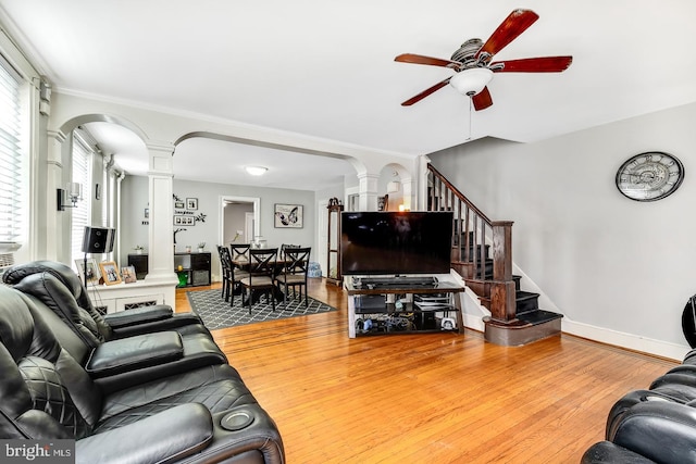 living room with ornate columns, stairway, arched walkways, and light wood-style floors